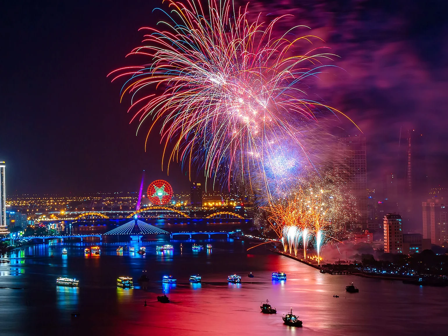 Fireworks over the Han River in Da Nang, with lit bridges and tour boats on the water