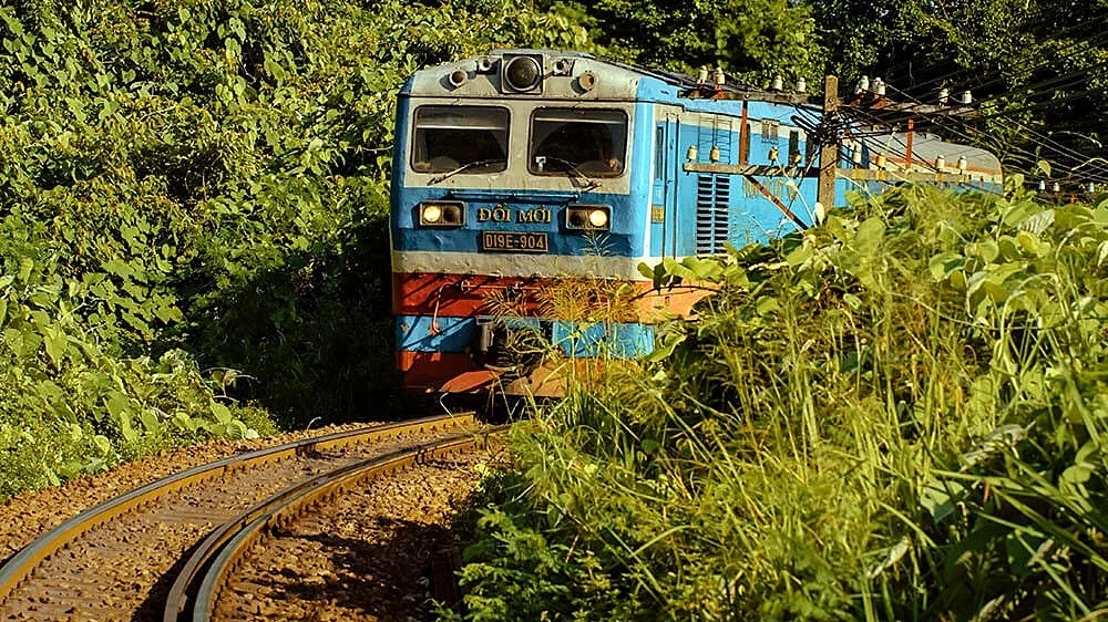 A blue diesel locomotive coming round a curve on a forest railway line
