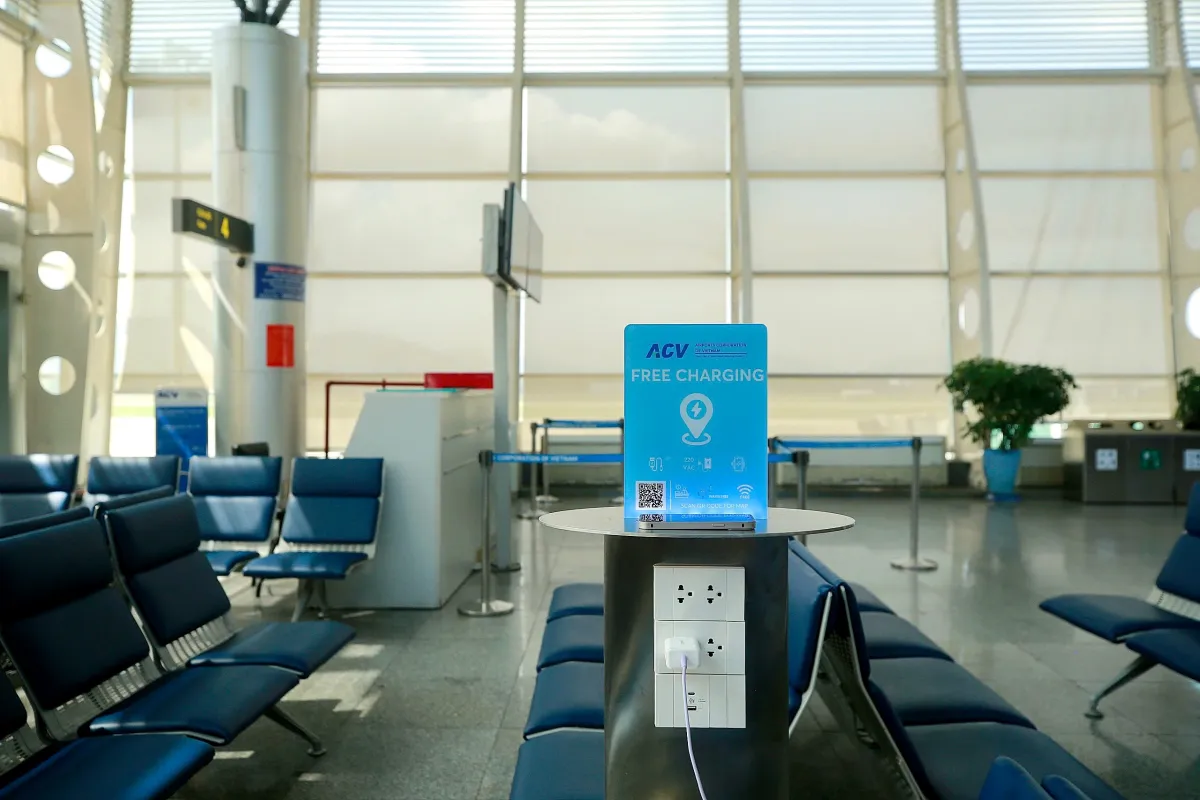 A free phone charging point with a charging cable plugged in, next to rows of seats at Da Nang International Airport