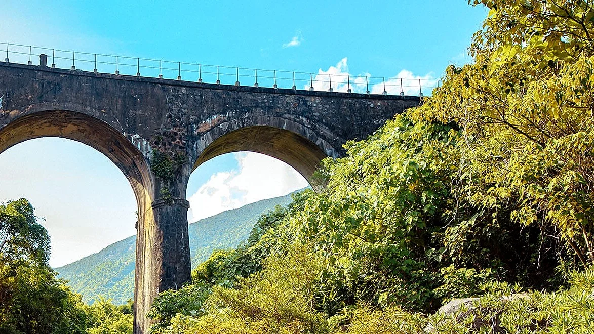A railway bridge with two arches on the Hai Van Pass, seen from below with green hills behind
