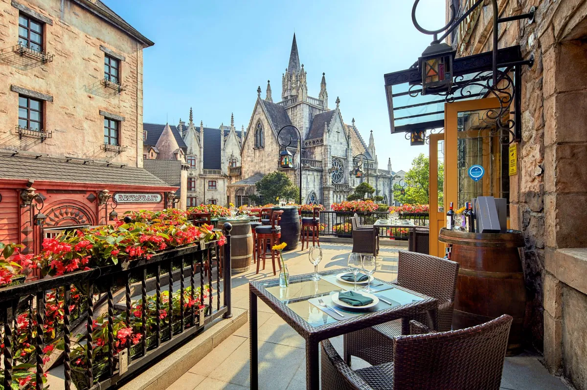 A restaurant terrace with flowers looking onto the church in the French Village at Ba Na Hills