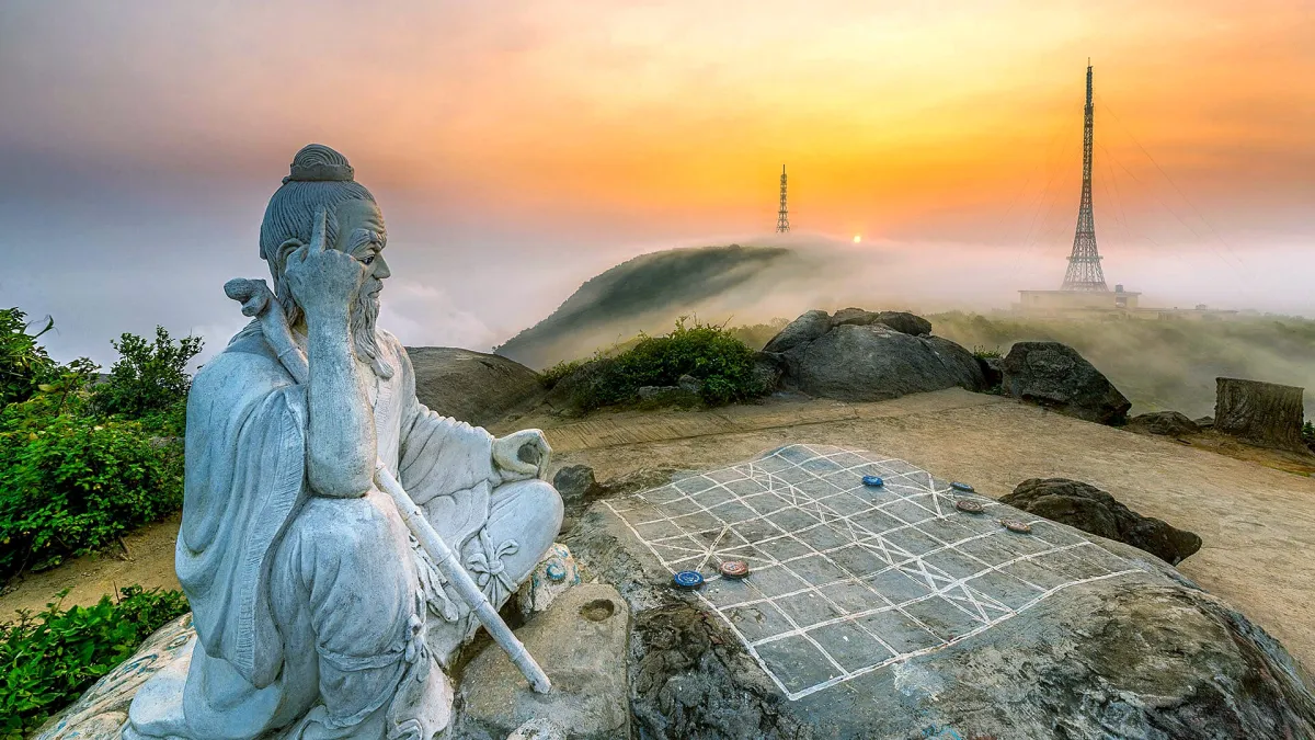 A stone statue of an old man playing chess on Ban Co peak on the Son Tra peninsula at sunset