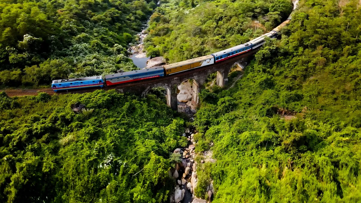 A train crossing a viaduct through green forest on the Hai Van Pass near Da Nang