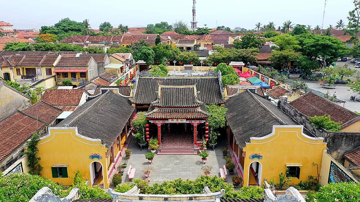 Aerial view of the Hainan Assembly Hall with yellow side wings around a stone courtyard and a red-pillared front hall