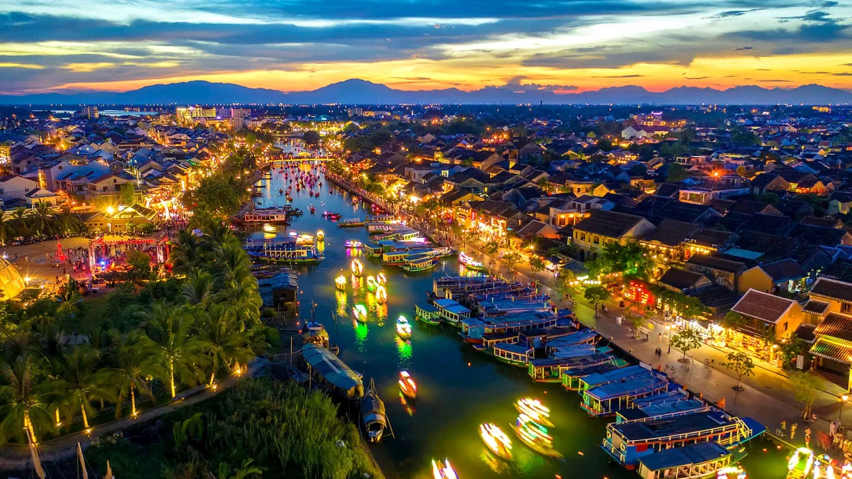 Aerial view of the Hoai River in Hoi An at dusk, with lit boats on the water