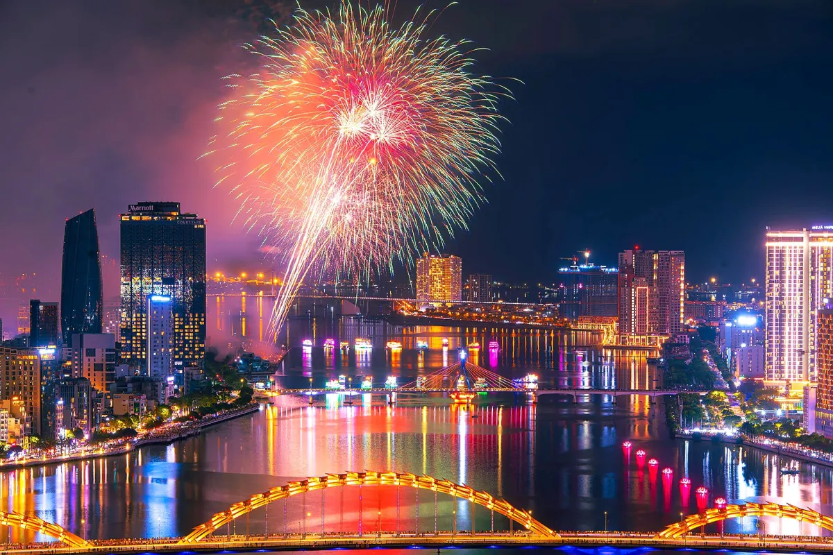 Fireworks over the Han River at night, with high-rise buildings, a swing bridge and the lit Dragon Bridge