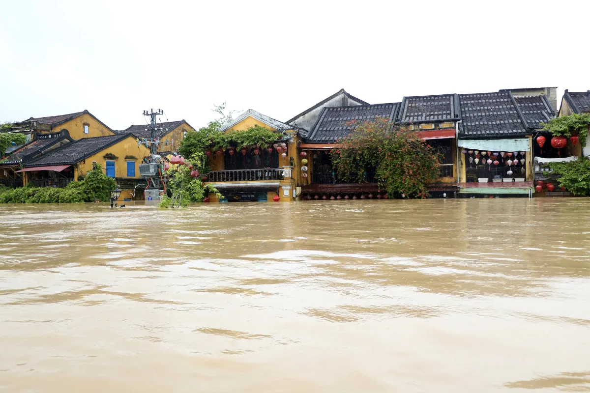 Old yellow houses with tiled roofs and lanterns in Hoi An, with brown floodwater up to their shopfronts