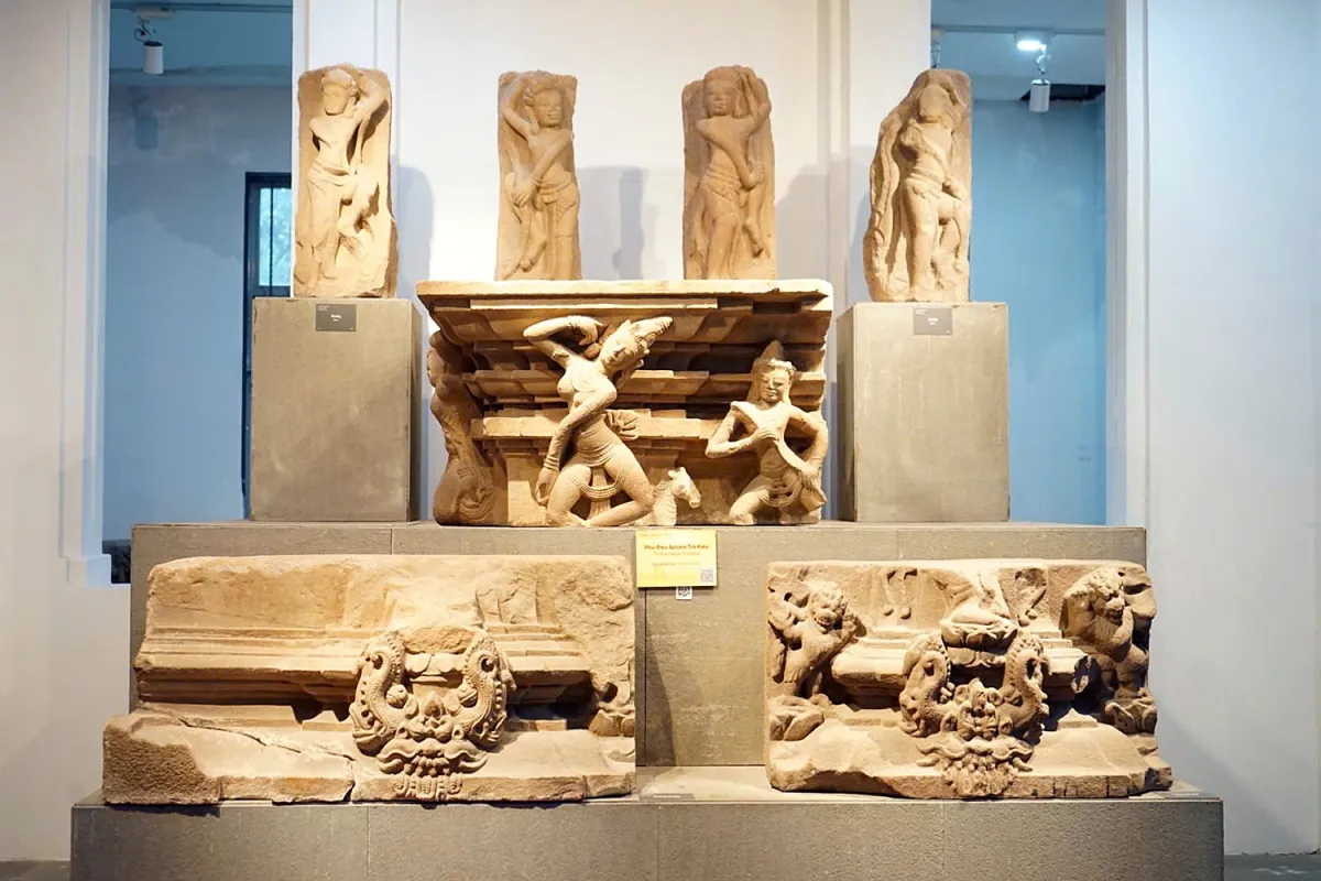 Sandstone carvings of dancers above a stone pedestal with two dancing figures, with two carved blocks with monster faces below