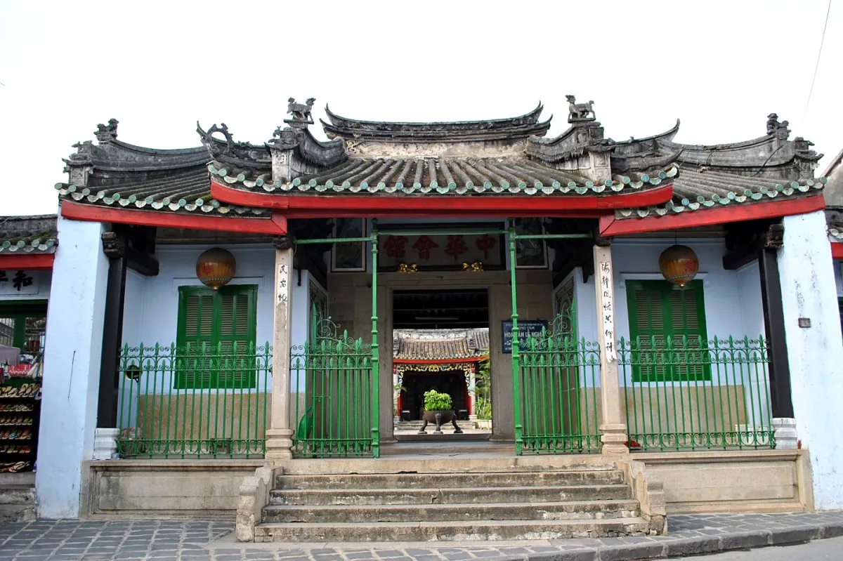 Street front of the Chinese Assembly Hall with a curved tiled roof, green iron railings, green shutters and an open gate onto the courtyard
