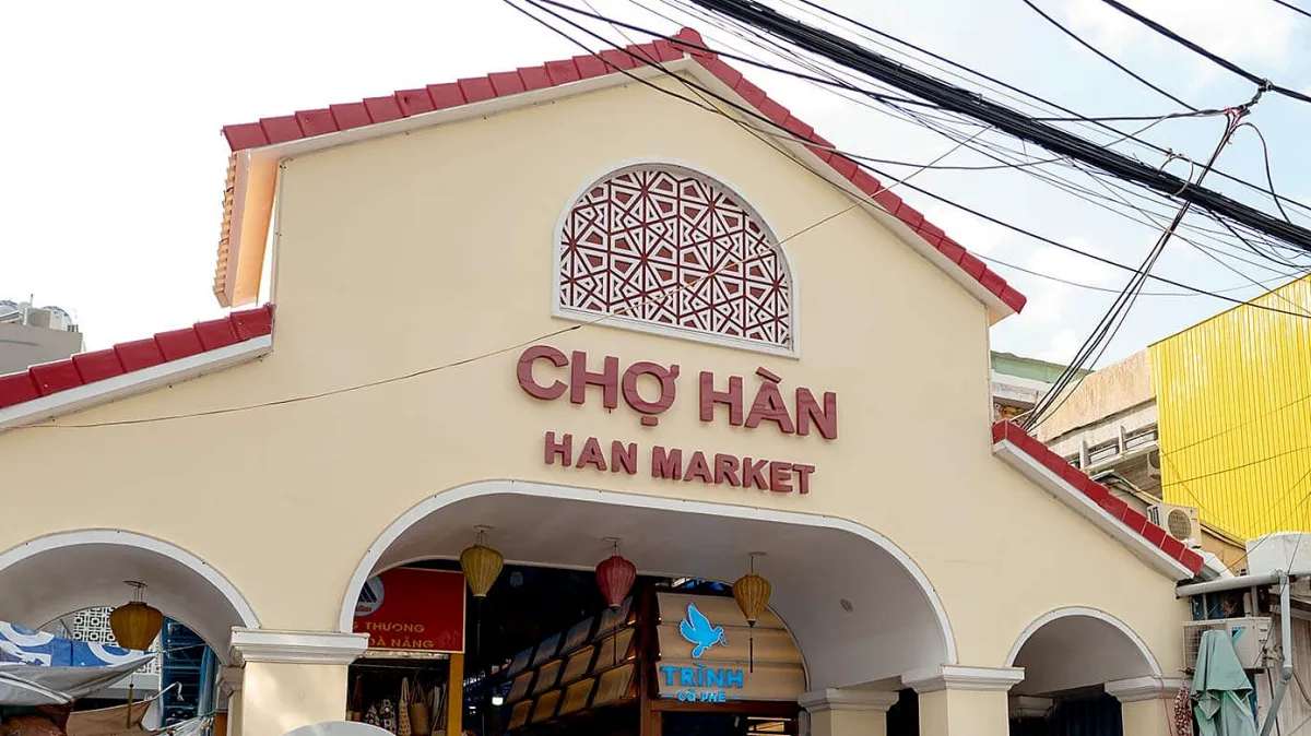 The cream-colored gatehouse of Han Market with a red tiled roof, the words Cho Han and Han Market above three arches hung with lanterns