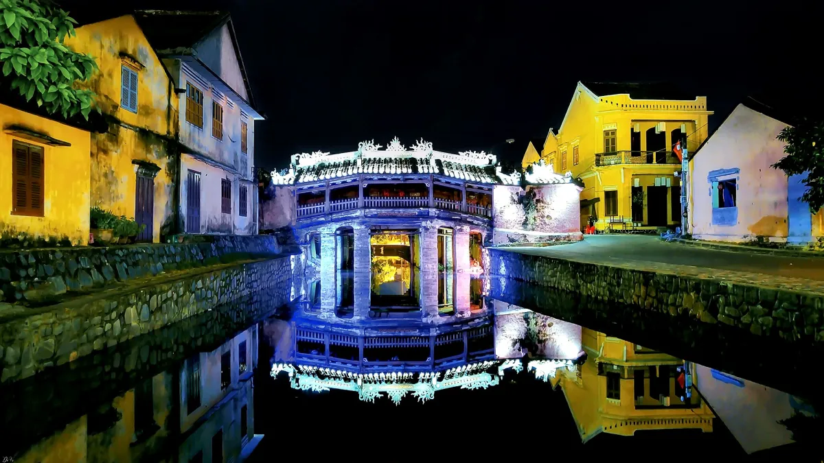 The Japanese Covered Bridge in Hoi An at night, lit up and reflected in the water