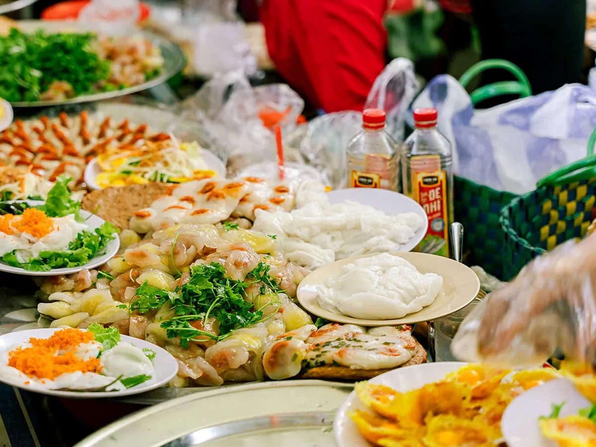 Trays of bánh bèo, rice dumplings and other snacks at a Con Market food stall
