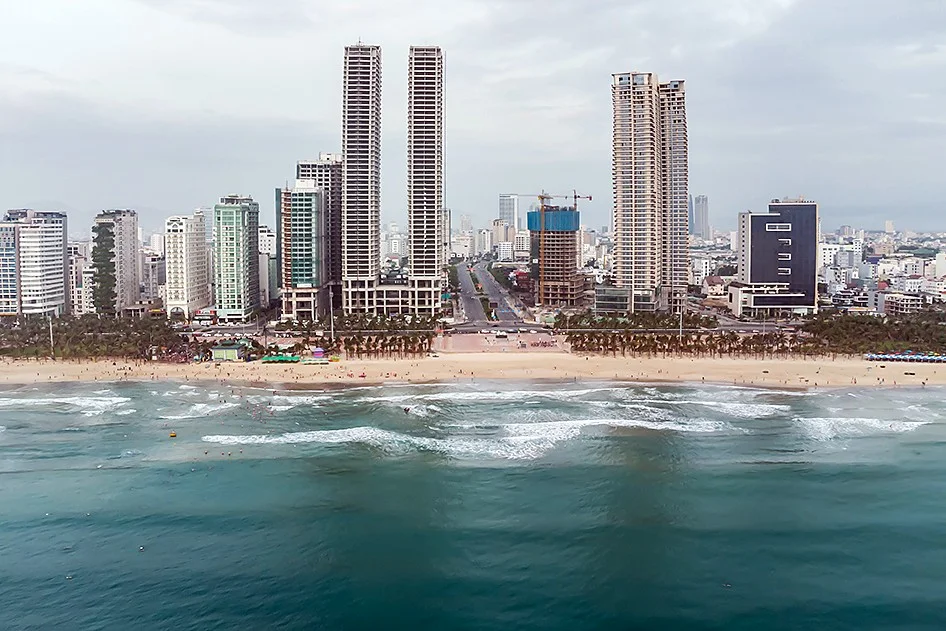 Twin high-rise towers and other buildings along the beach road, seen from the sea